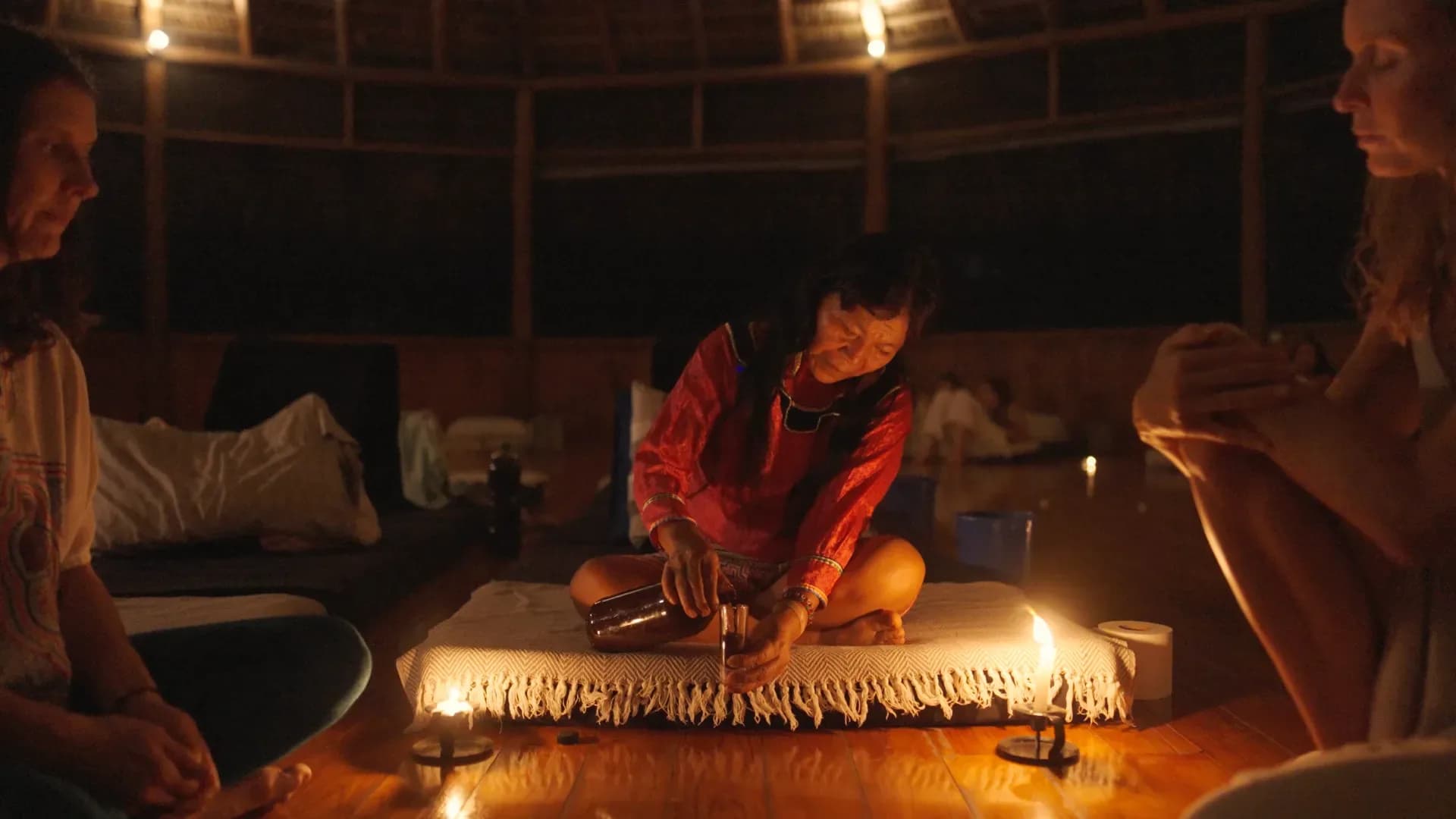 Facilitator pouring ceremonial medicine by candlelight