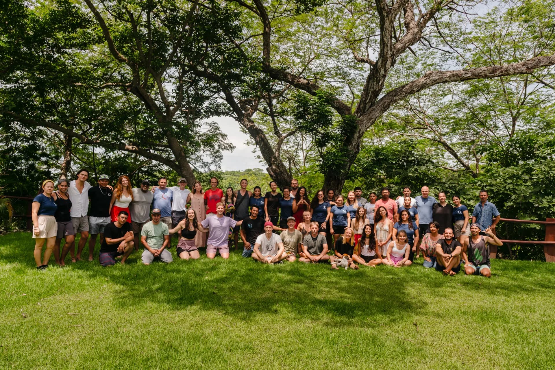 A group of Soltara team members standing together in a lush jungle setting, smiling and looking at the camera.